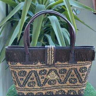 Bolso de paja con asas de piel, forrado de tela, tira de flecos y aplique metalico